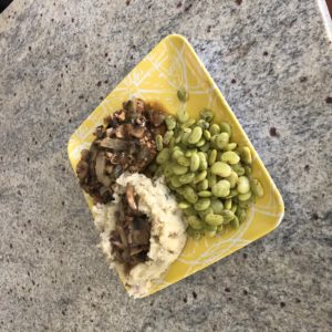 A yellow plate of prison loaf with mashed potatoes, wild mushroom gravy and a side of ancient frozen lima beans.